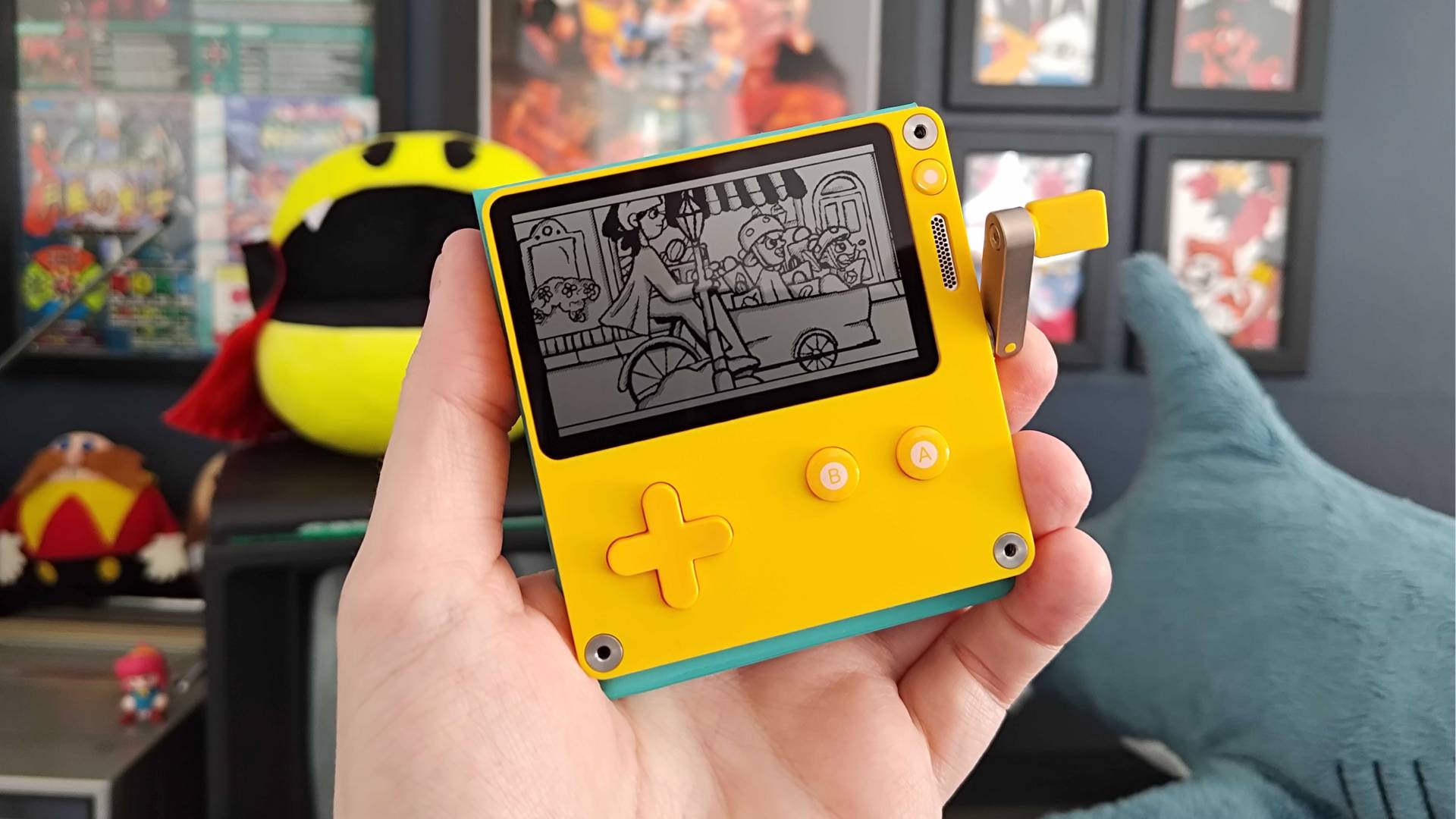 Hand holding Playdate handheld with Wheelsprung game on screen.