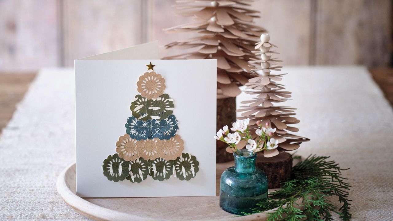 Handmade Christmas card beside tree decoration and vase of flowers