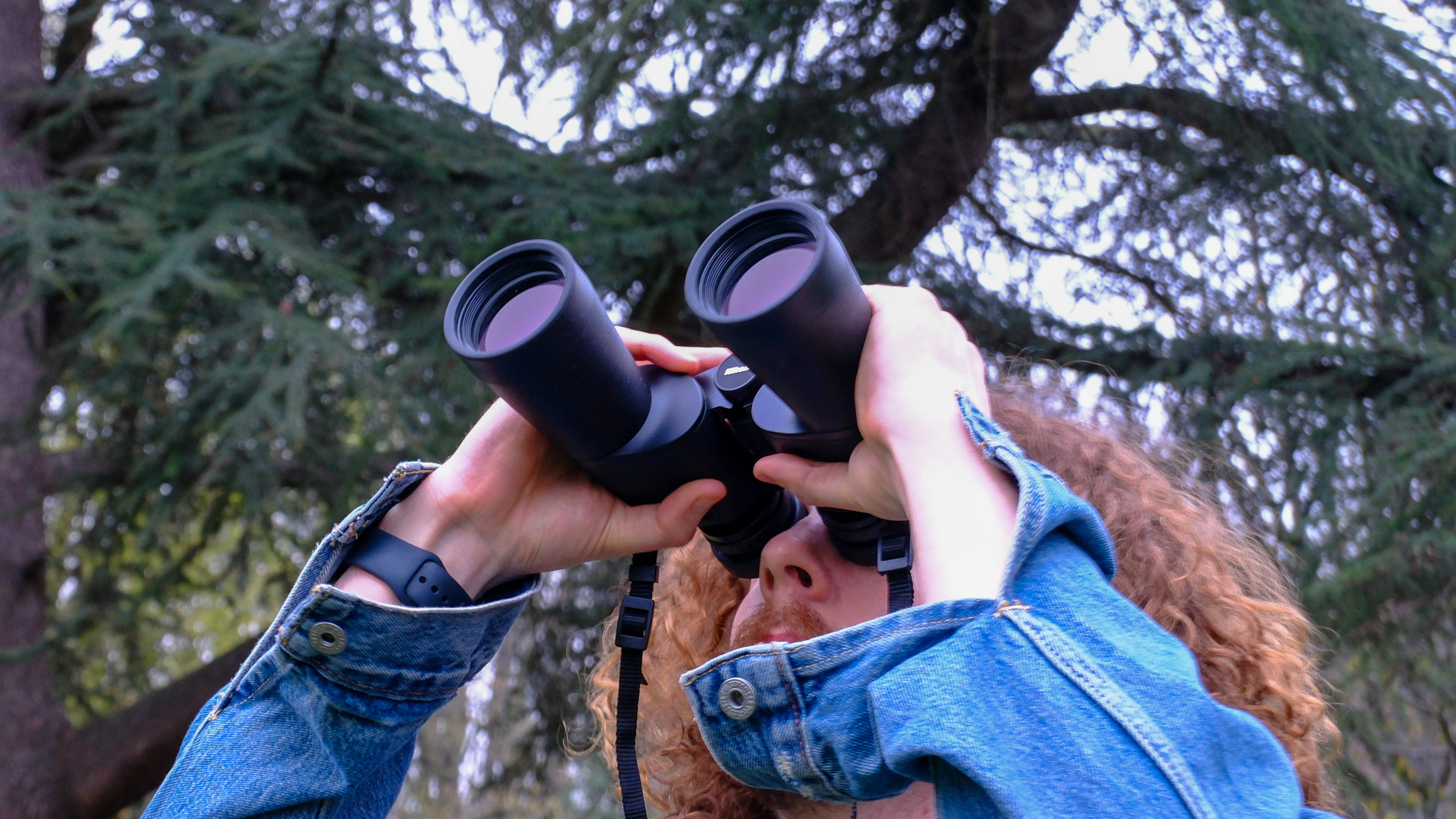 A man looking upwards through the Nikon Action 16x50 binoculars.