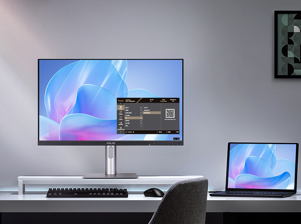 The Asus ProArt PA27JCV monitor sitting on a desk next to a laptop