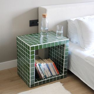 Green tiled side table next to a bed