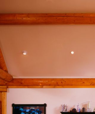 A white ceiling with wooden beams, recessed lighting and decor underneath it