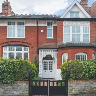 Red brick Edwardian house front garden screened by hedges and brick wall