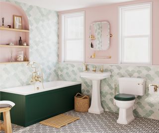 green panelled bath in a bathroom with pink walls and white sanitaryware