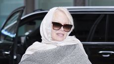 Pamela Anderson wearing a white silk scarf and dark sunglasses