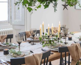 dining table set up for christmas with hanging foliage and candles