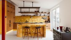 A kitchen with wooden wall cabinetry on one end, a yellow zellige tile backsplash, and a matching curved island