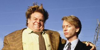 Tommy (Chris Farley) smiles cheekily while standing with an arm around a serious-looking Richard (Da