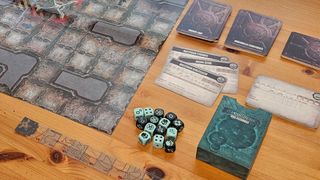 The board, dice, cards, and tokens of Necromunda: Hive Secundus on a wooden table