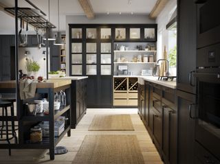 a dark kitchen high, glass fronted cabinets with island and butcher's block by ikea