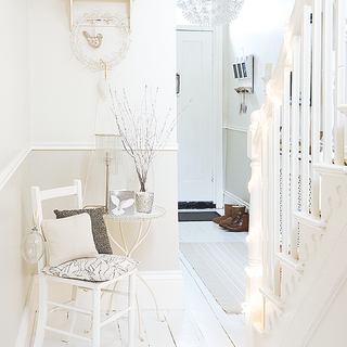hallway with white wall white chair and white wooden flooring