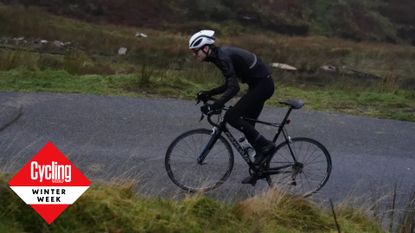 Image shows cyclist climbing up hill during a winter training ride