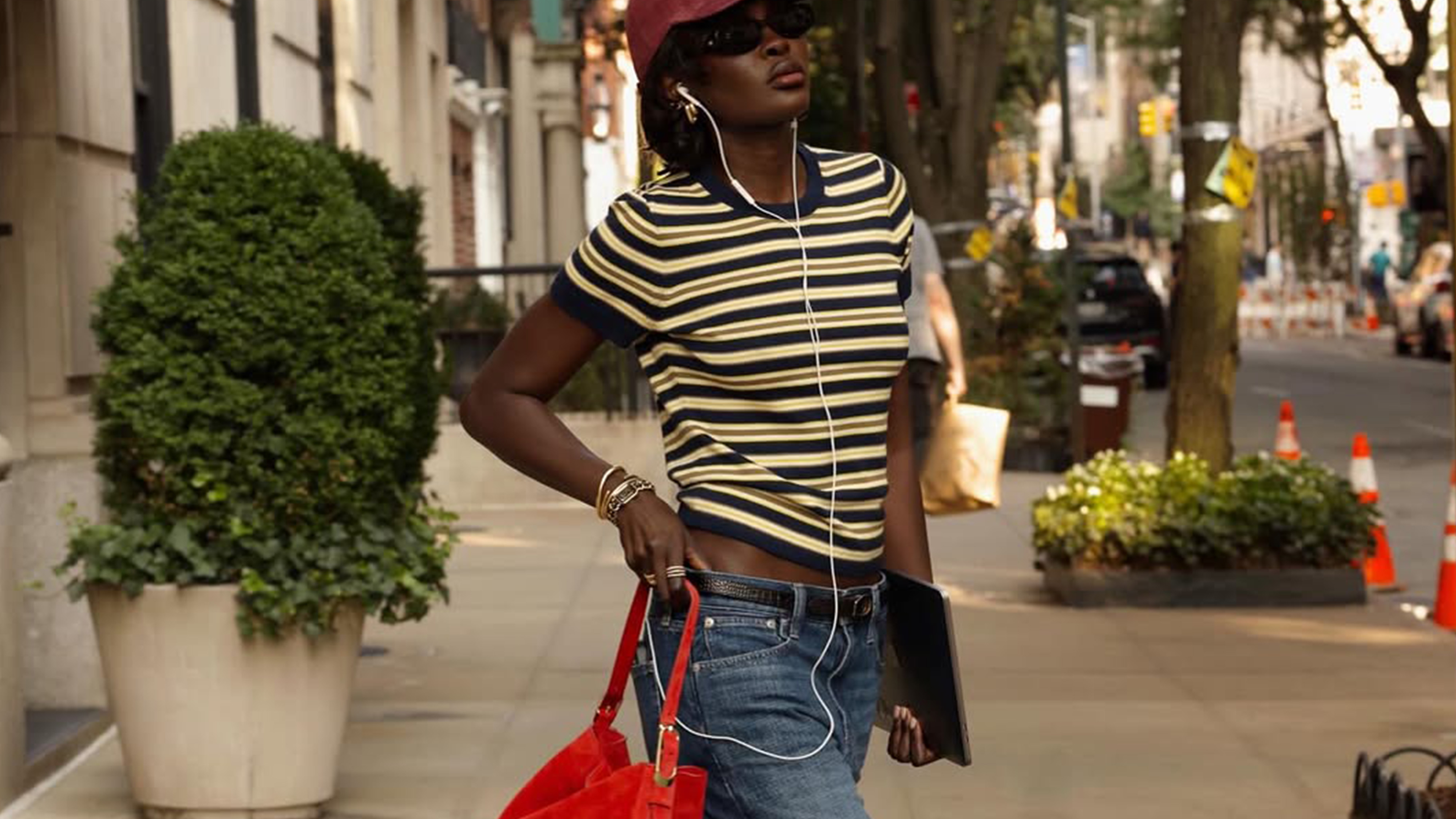 Woman wearing striped shirt styled with a baseball hat and jeans.