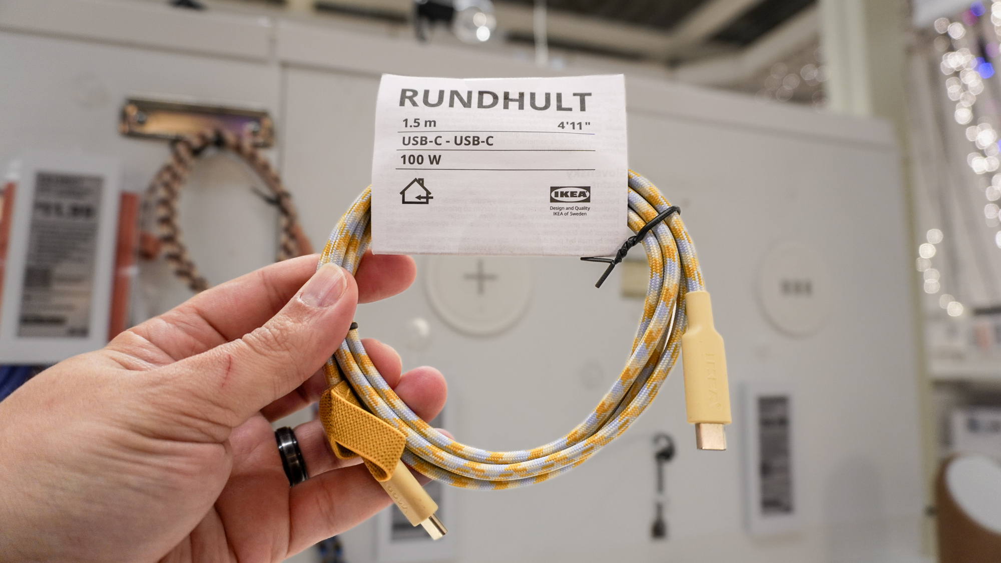 A person holding a RUNDHULT USB-C to USB-C cable in hand at IKEA