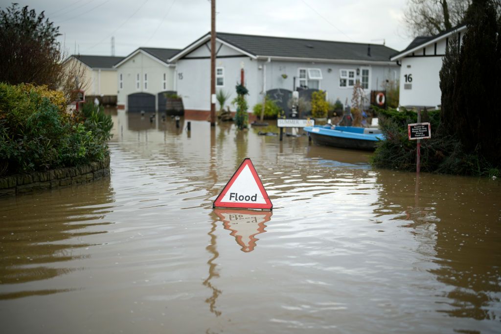 A sign that says &#039;flood&#039; sits in deep water in a residential street with the incident likely to have led to home insurance claims (image: Christopher Furlong/Getty Images)