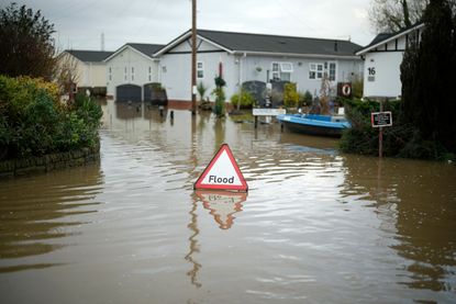 A sign that says 'flood' sits in deep water in a residential street with the incident likely to have led to home insurance claims (image: Christopher Furlong/Getty Images)