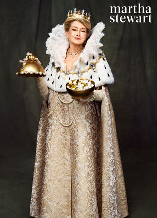 Martha Stewart wearing a ruffled white head dress and crown with a gold queen costume while holding a candy dish