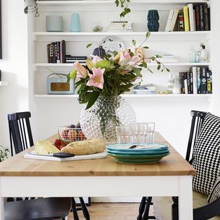dining room with dining table and shelves with flower on glass jar
