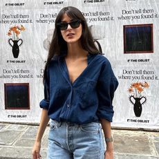 @leiasfez wearing a navy blue button-down shirt with jeans and sunglasses.