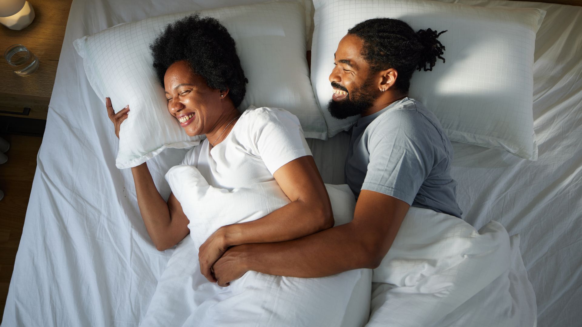 Couple spooning and laughing together in bed