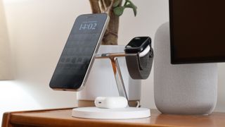 Belkin BoostCharge Pro 3-in-1 Wireless Charger with attached iPhone, AirPods, and Apple Watch on a wooden desk