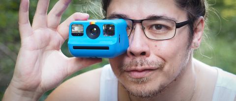 Photographer James Artaius holding a Blue Polaroid Go Gen 2 camera, in a woodland setting