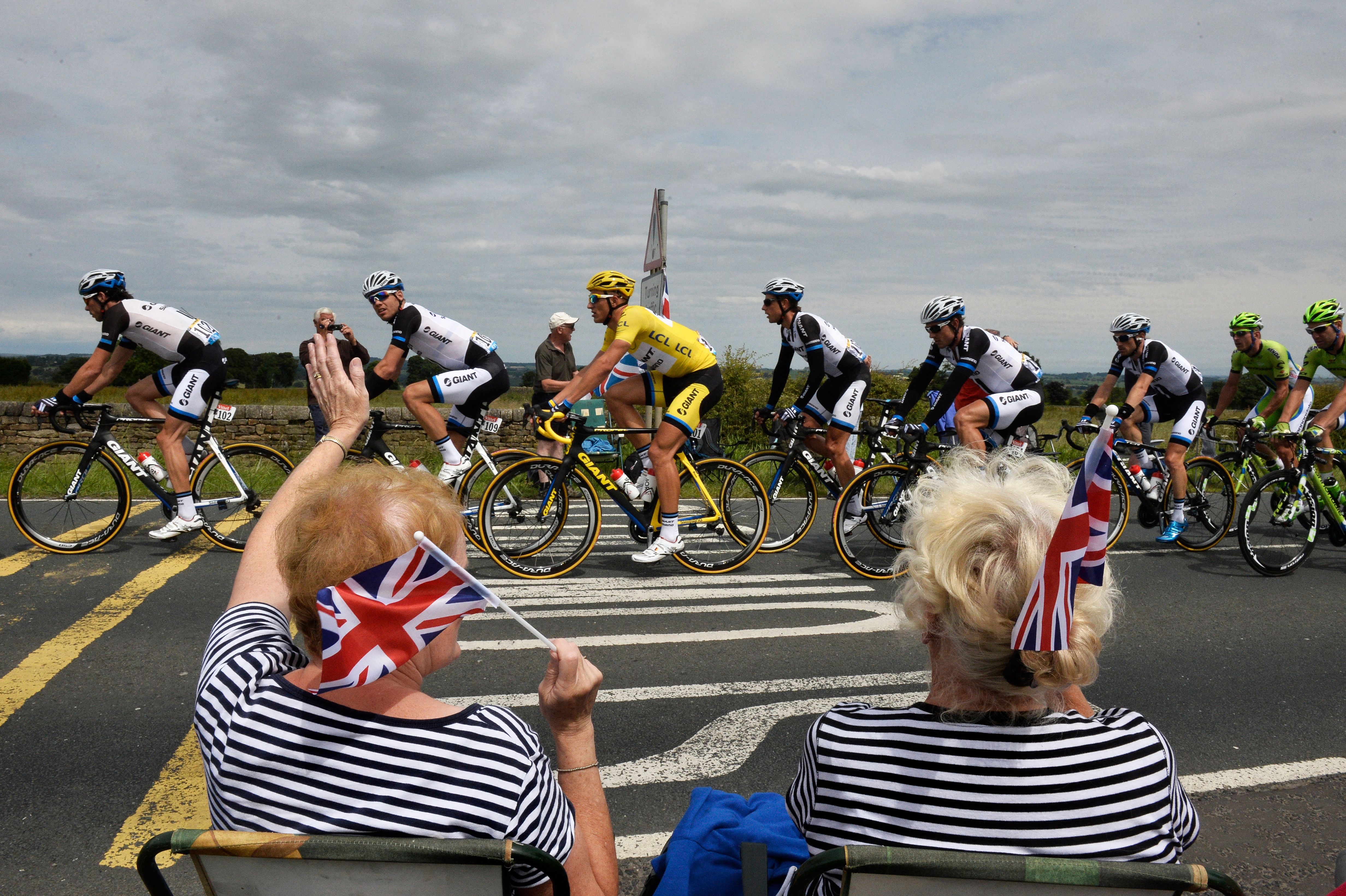 TOPSHOT - Supporters wave along the road as Germany&#039;s Marcel Kittel (C), wearing the overall leader&#039;s yellow jersey, rides past during the 201 km second stage of the 101st edition of the Tour de France cycling race on July 6, 2014 between York and Sheffield, northern England. AFP PHOTO / JEFF PACHOUD (Photo by Jeff PACHOUD / AFP) (Photo by JEFF PACHOUD/AFP via Getty Images)