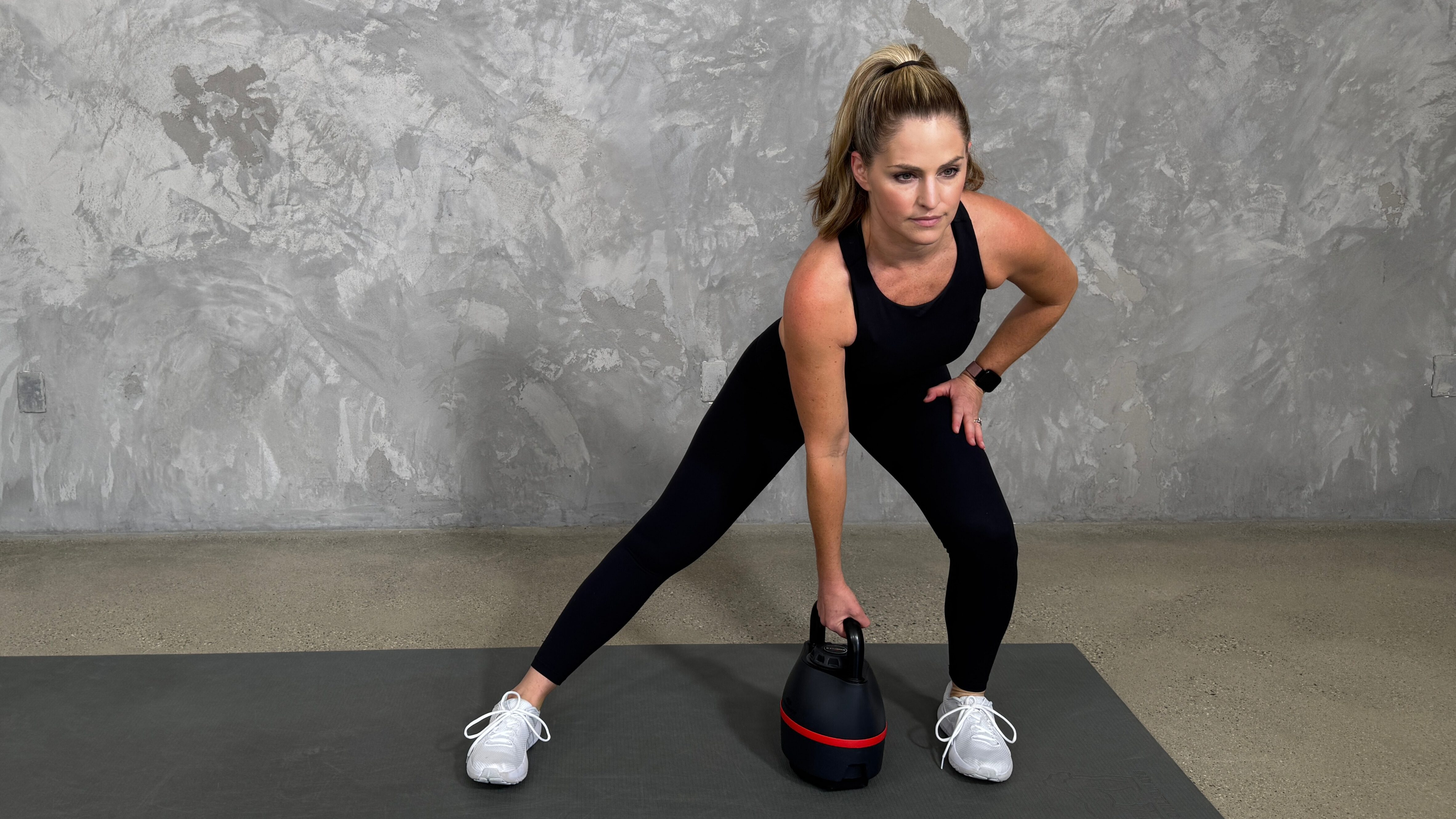Woman in blue sportswear exercises with kettlebell