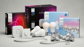 Various Philips Hue smart lights and accessories with their packaging on grey stone background