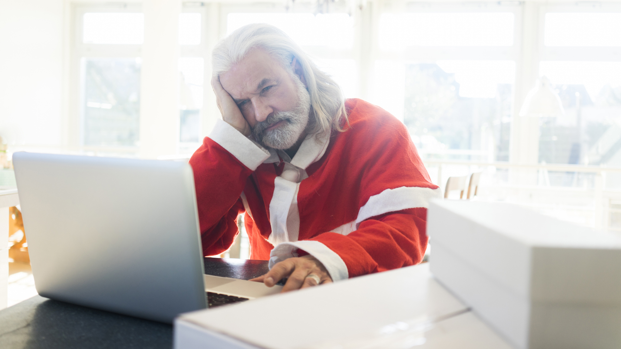 Man with grey hair dressed as Santa using a laptop
