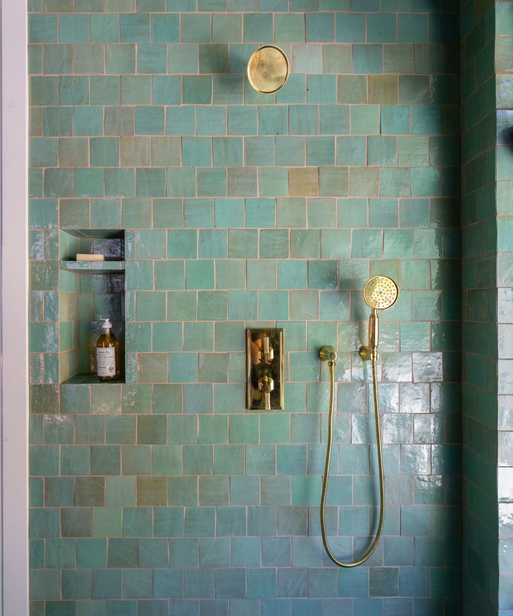 A shower area with blue tiles and brass fixtures