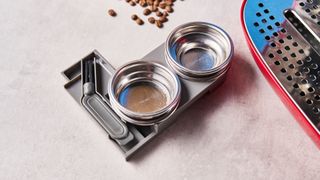 a red smeg espresso machine with burr grinder is photographed against a blue background