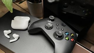 AirPods on top of an Xbox next to a controller