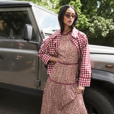 Model wearing a floral tiered dress and burgundy gingham over shirt sold at Nobody's Child