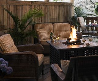 A covered wooden deck with fire pit table