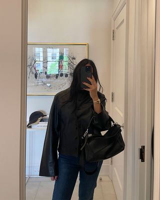 A woman taking a mirror selfie and holding a Loewe Puzzle bag.