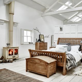 A bedroom with high ceilings, exposed beams and a fireplace