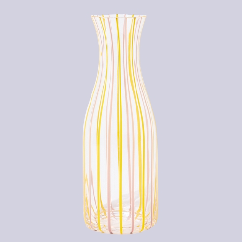 yellow and pink striped glass vase in front of a lilac background.