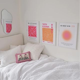 Three pink and orange posters on white walls