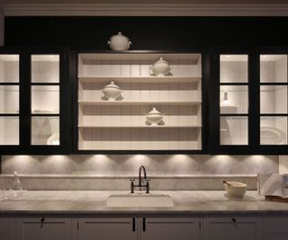 Classic kitchen with marble countertops and open shelving, illuminated by subtle under-cabinet lighting