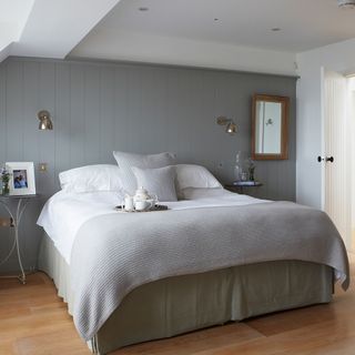 main bedroom with panelled wall and wooden flooring