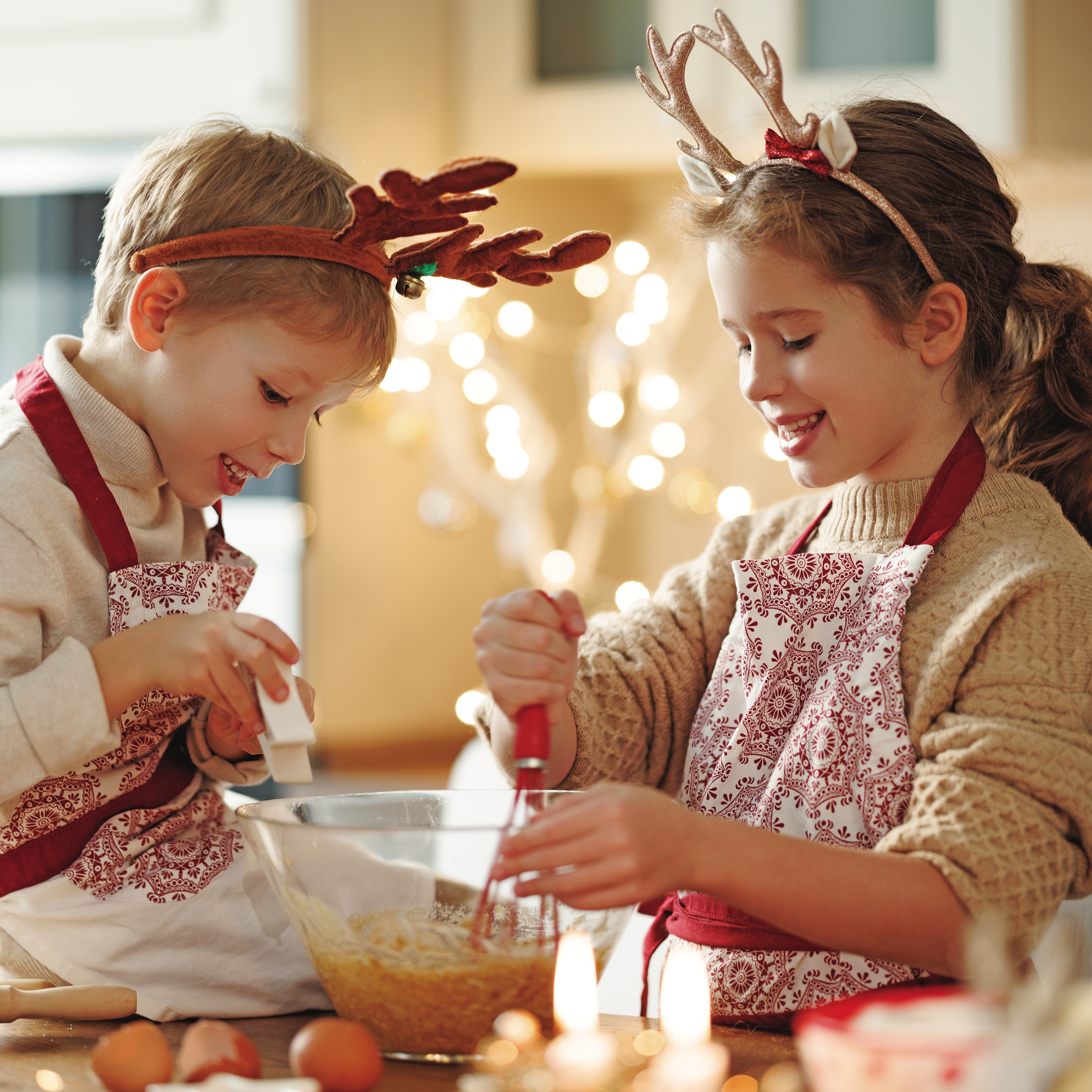 Two children wearing festive headwear cooking together