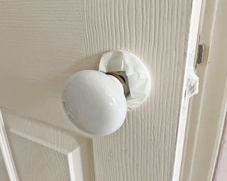 White masking tape wrapped round a door knob to protect it before Painting