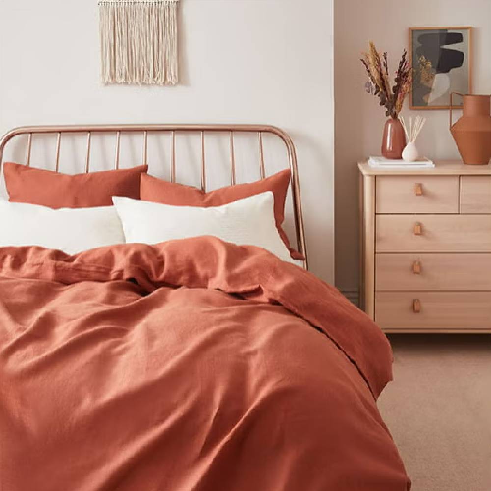 A modern, bohemian style bedroom with rust coloured bedding and home furnishings from The Hut.
