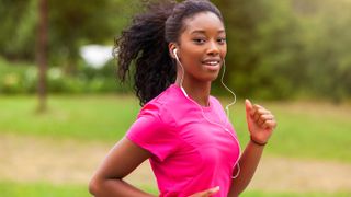 Check out the best running headphones of 2021. Here, a close-up of a woman running while wearing earbuds.