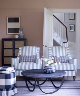 Two striped armchairs stand next to each other in a room with pink walls.