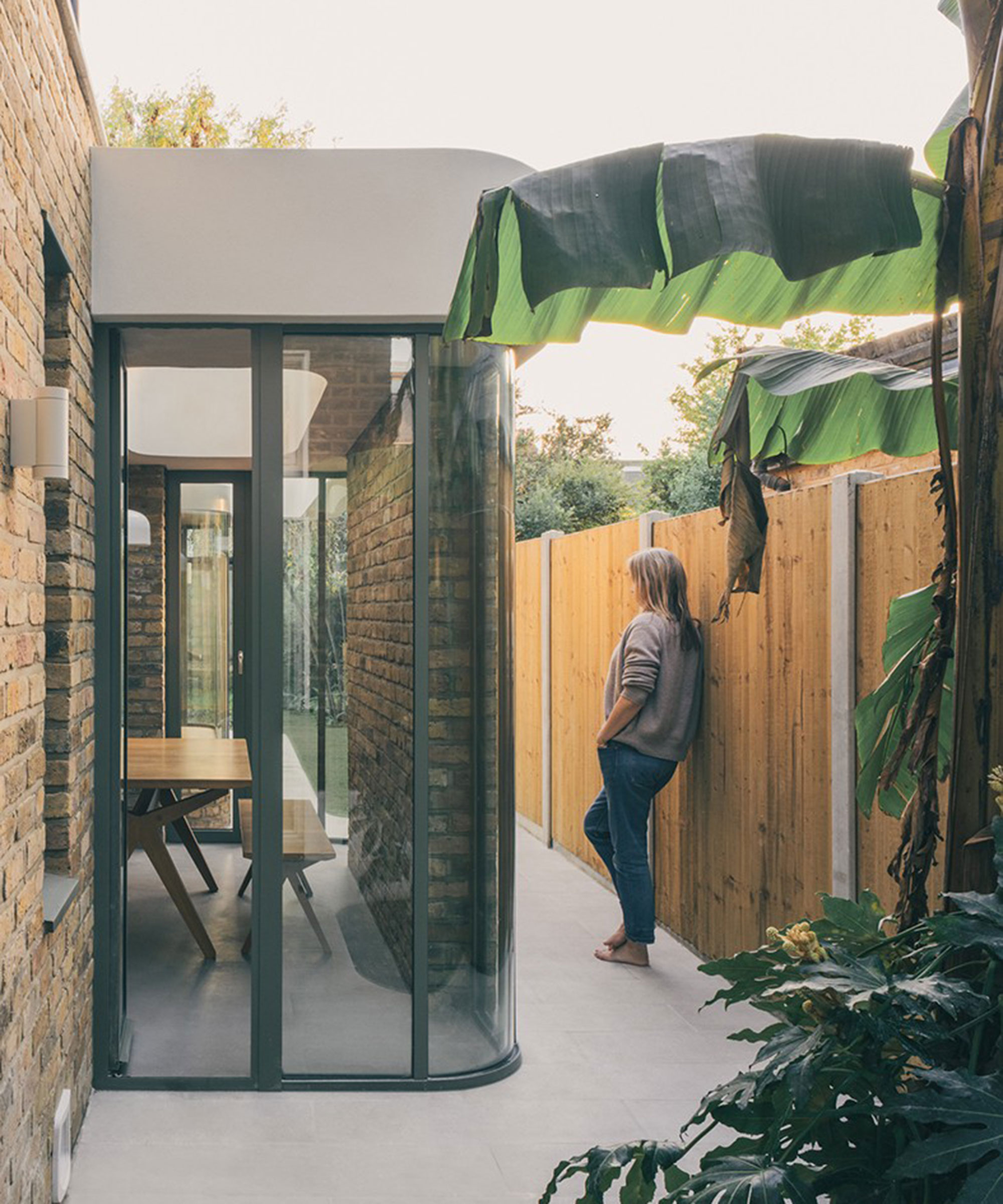 small curved glass extension with view of banana tree