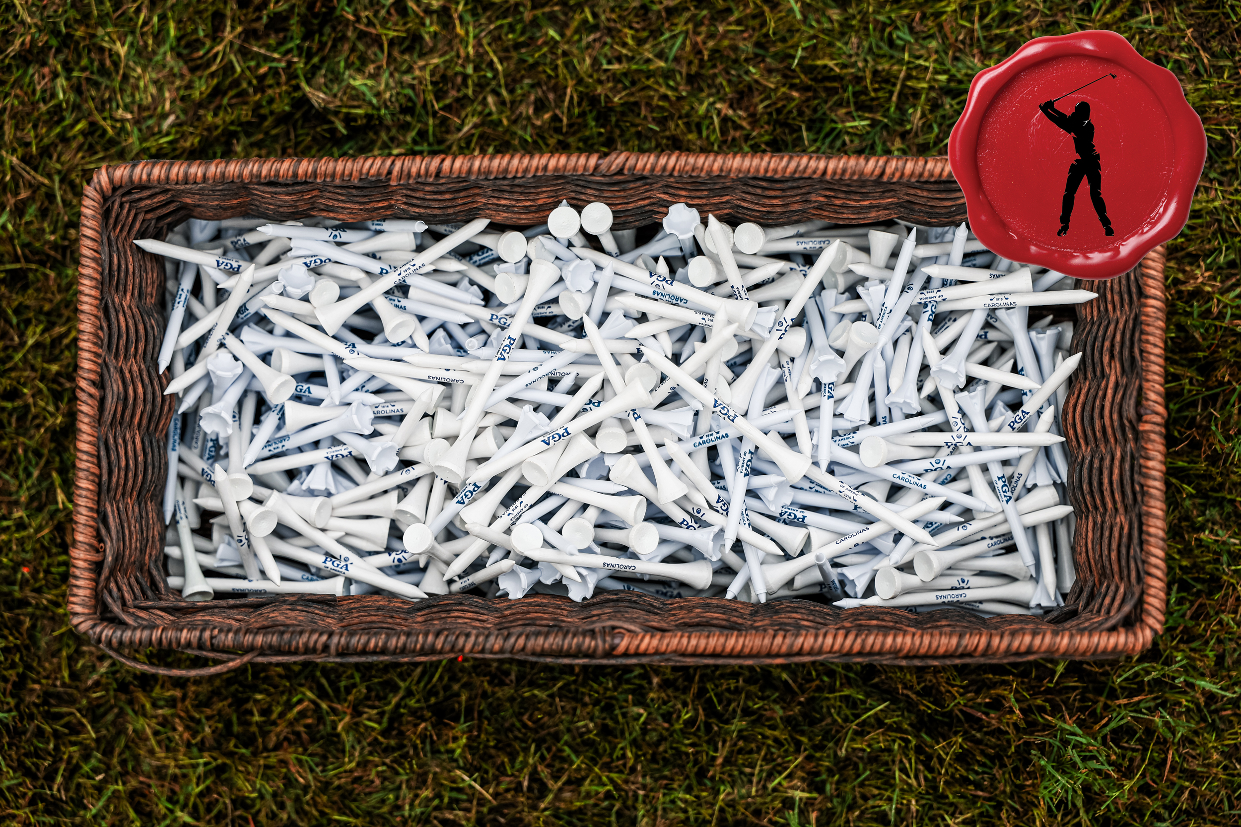 Looking down at a box full of white tees with a red Secret Club Golfer logo in the top-right
