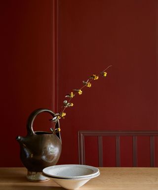 bronze red by little greene painted on a kitchen wall with a wooden table and japandi style