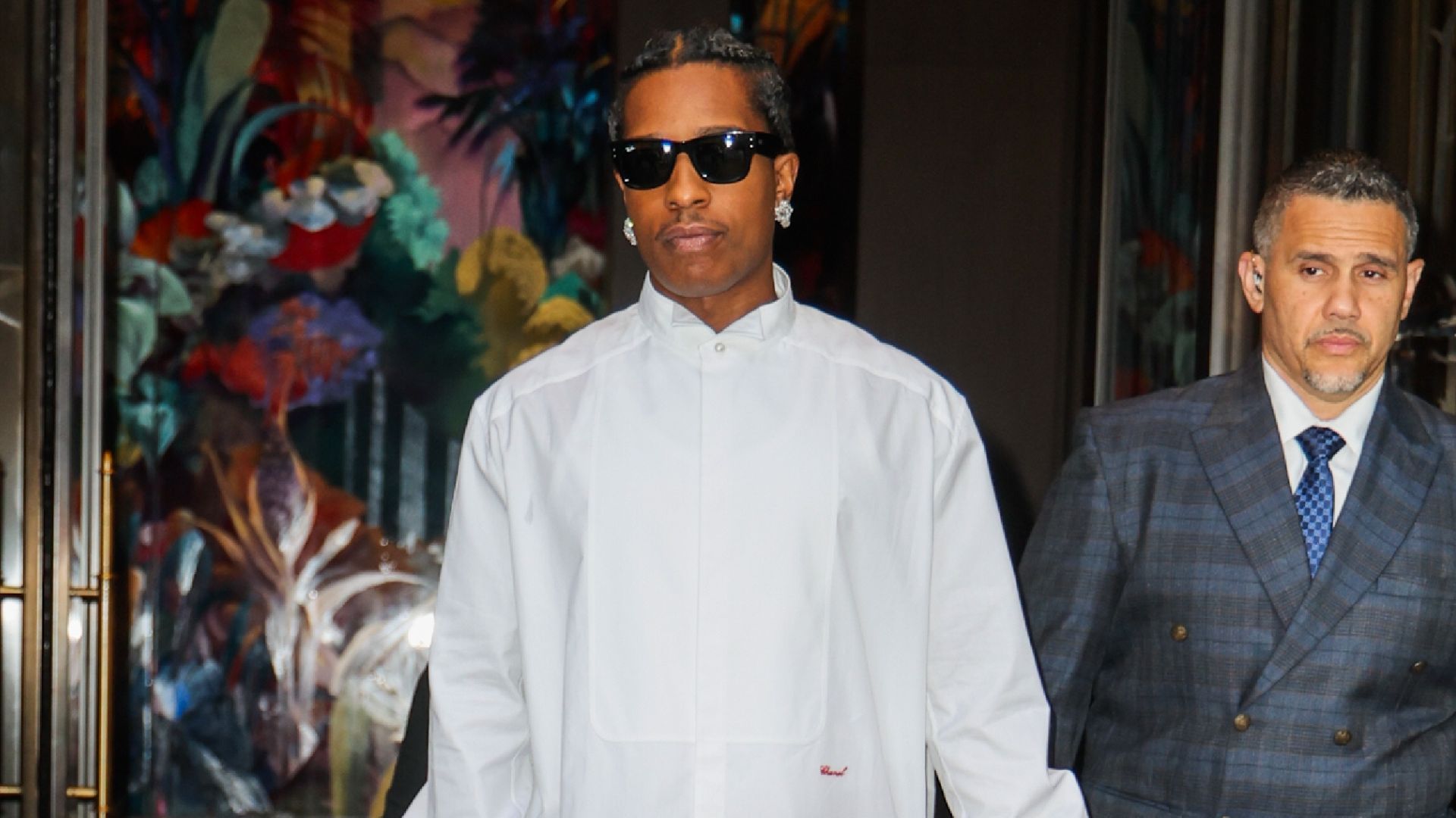 Asap Rocky steps outside wearing a red Chanel bag with a white shirt and black trousers.